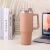 Brown tumbler with handle and straw on desk with laptop and books