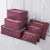 6 piece burgundy travel organizer set for suitcases on a bed