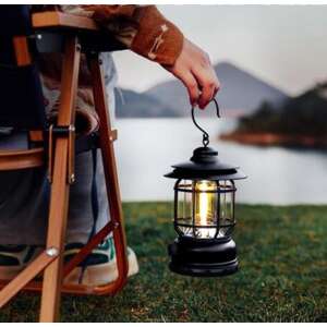 Black camping lantern hanging from a hook, person holding it in a camping setting - Camping & Hiking