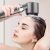 Woman using high-pressure shower head for hair washing