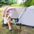 Woman sitting in a Springos® camping tent with awning, using a phone
