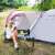Woman sitting in a Springos® camping tent with awning, using a phone
