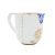 Royal porcelain creamer with gold polka dots and floral design, angled view