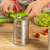 Woman using Kuhn Rikon green can opener to open a can of food