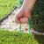 Green metal U-shaped garden stakes securing artificial grass