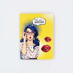 Yellow notebook with a pop art design of a woman with glasses and the text 'You are amazing' on the cover - Nekupto