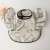 Close-up view of the beige baby bib with a cute cartoon design, featuring a pocket to catch food, perfect for messy eaters.