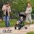 Chicco GLEE stroller, black frame with colorful floral canopy, parents and child enjoying a walk in the park