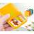 Yellow Flippy pill box with 2 compartments, filled with pills, hand holding it open