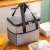 Grey insulated lunch bag with black handles and zipper, sitting on a wooden table with food containers, perfect for carrying food and drinks to work, school, or picnics