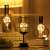Flippy wine glass shaped LED table lamp with warm white light on a table with other lamps