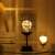 Flippy wine glass shaped LED table lamp with warm white light on a table with books