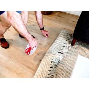 Man using double-sided adhesive tape to secure a rug to the floor - Hobby glue