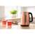 Sencor SWK 7002CO copper electric kettle, on a kitchen counter with tea and pastries