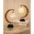 TWIRL STAR crescent moon table lamp with a white rattan ball and a star-shaped lampshade, black metal base, on a table with books