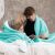 Family reading a book under AmeliaHome SHLEEPY turquoise blanket
