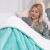 Woman relaxing in bed with a turquoise SHLEEPY blanket