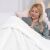 Woman relaxing in bed with AmeliaHome SHLEEPY white blanket and tablet