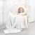 Girl wrapped in AmeliaHome SHLEEPY white blanket sitting in a hanging chair