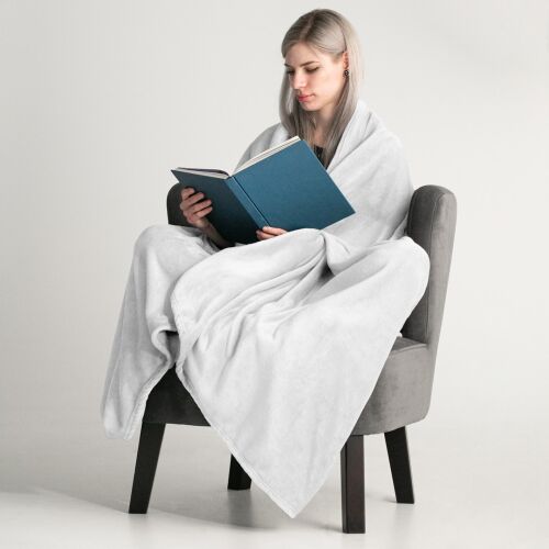 Woman wrapped in DecoKing MIC white microfiber blanket reading a book