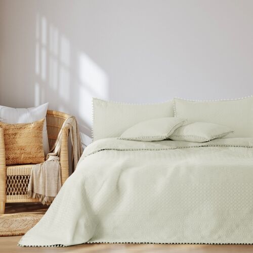 AmeliaHome Meadore cream bedspread with pom poms on a bed in a bedroom setting