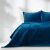 AmeliaHome Laila indigo blue velvet bedspread on bed with pillows in bright setting