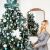 Woman decorating Royal Trees Diamond Fir Christmas Tree with blue ornaments