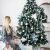 Royal Trees Diamond Fir Christmas Tree decorated in a bedroom setting with a woman
