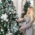 Woman decorating Royal Trees Diamond Fir Christmas Tree with blue and white ornaments
