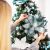 Woman decorating Royal Trees Diamond Fir Christmas Tree with a large flower ornament