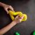 Child's hands playing with a yellow bendable and stretchable tube, forming a shape
