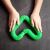 Child's hands playing with a green bendable and stretchable tube, forming a shape