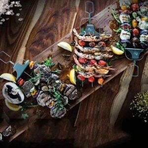 Zestaw szaszłyków Grillmester: Trzy szaszłyki z różnymi grillowanymi potrawami, w tym krewetkami, warzywami i mięsem, na drewnianej desce do serwowania. - Grillowanie i gotowanie na świeżym powietrzu