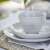 MANOR világosszürke kőedény tálka és tányérok, asztalterítésen