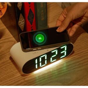 Biely digitálny budík so zeleným LED displejom, ktorý zobrazuje 10:23, počas nabíjania smartfónu - Dom&záhrada