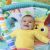 Baby lying on Bright Starts Wild Wiggles play mat smiling