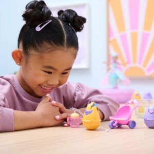 Ein junges Mädchen spielt mit Hatchimals Alive Spielzeug, darunter ein Kinderwagen, zwei Eier und eine Flasche - Spin Master Figuren