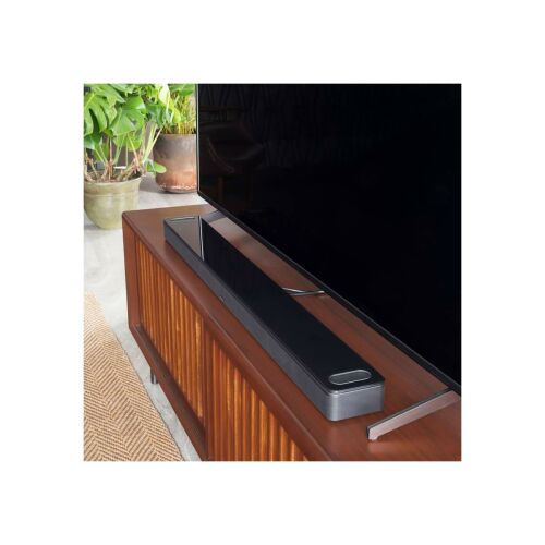 Fekete Bose Smart Ultra Soundbar egy TV alatt, fa szekrényen. Élvezze a magával ragadó házimozi hangzást Dolby Atmos technológiával. - Audio