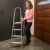 Woman using folding steel ladder in an office setting