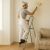 Man painting a wall using folding steel ladder