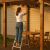 Woman using folding steel ladder to hang outdoor lights