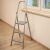 Foldable steel step ladder with 3 steps, next to a window