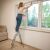 Woman cleaning window using foldable steel step ladder