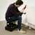 Man using the rolling chair with tool holder to fix a radiator