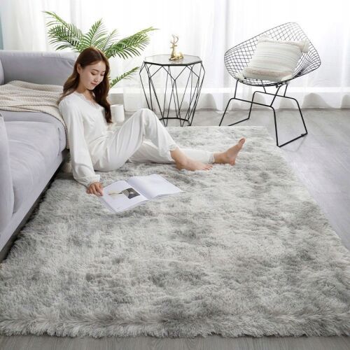 Frau entspannt sich auf einem hellgrauen Shaggy-Plüschteppich 100x150 cm im Wohnzimmer