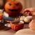 Kéz tart egy tea szűrőt egy csésze tea fölött, Halloween témájú környezet.