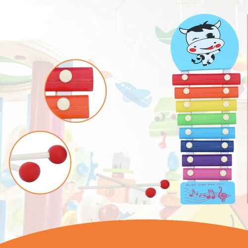 Közelkép egy tehén mintás xilofon játékról, színes hangjegyekkel és ütőkkel