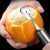Közelkép az Ergonomikus citrus hámozóról használat közben egy narancson.