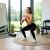 Nő guggolásokat végez ActiGet 4kg világos rózsaszín kettlebell-lel otthoni edzőteremben