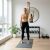 Nő overhead press-t végez ActiGet 4kg világos rózsaszín kettlebell-lel otthoni edzőteremben